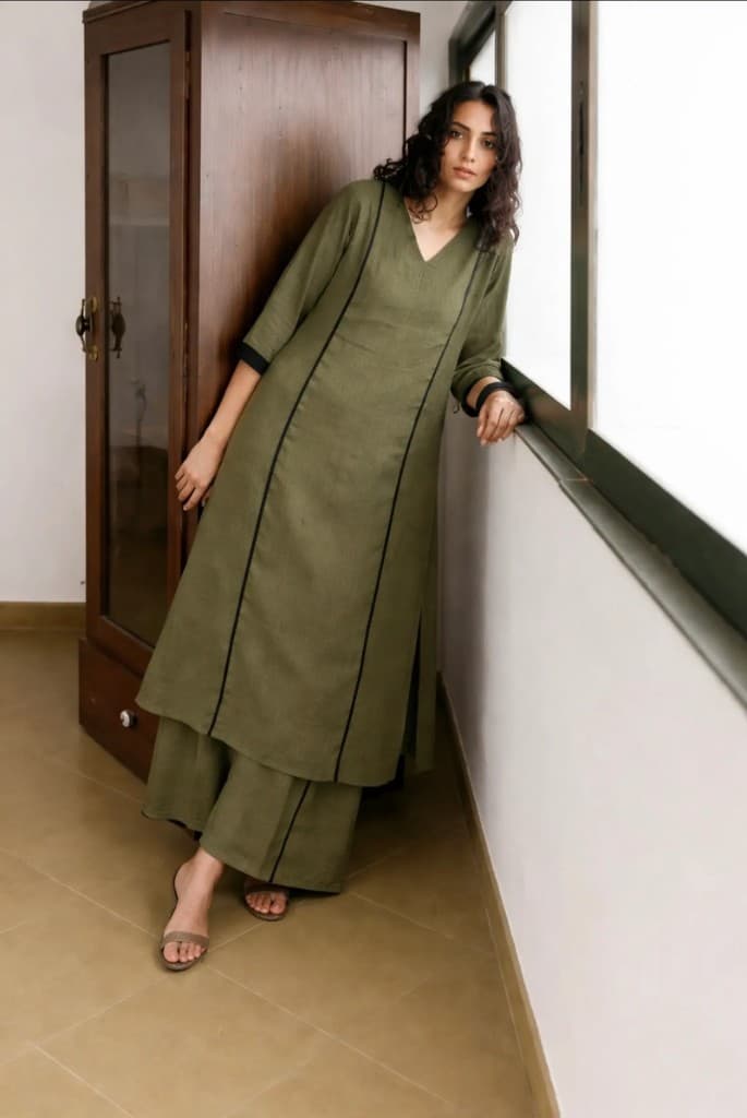 Woman wearing the Sage Dusk olive kurta set by a window